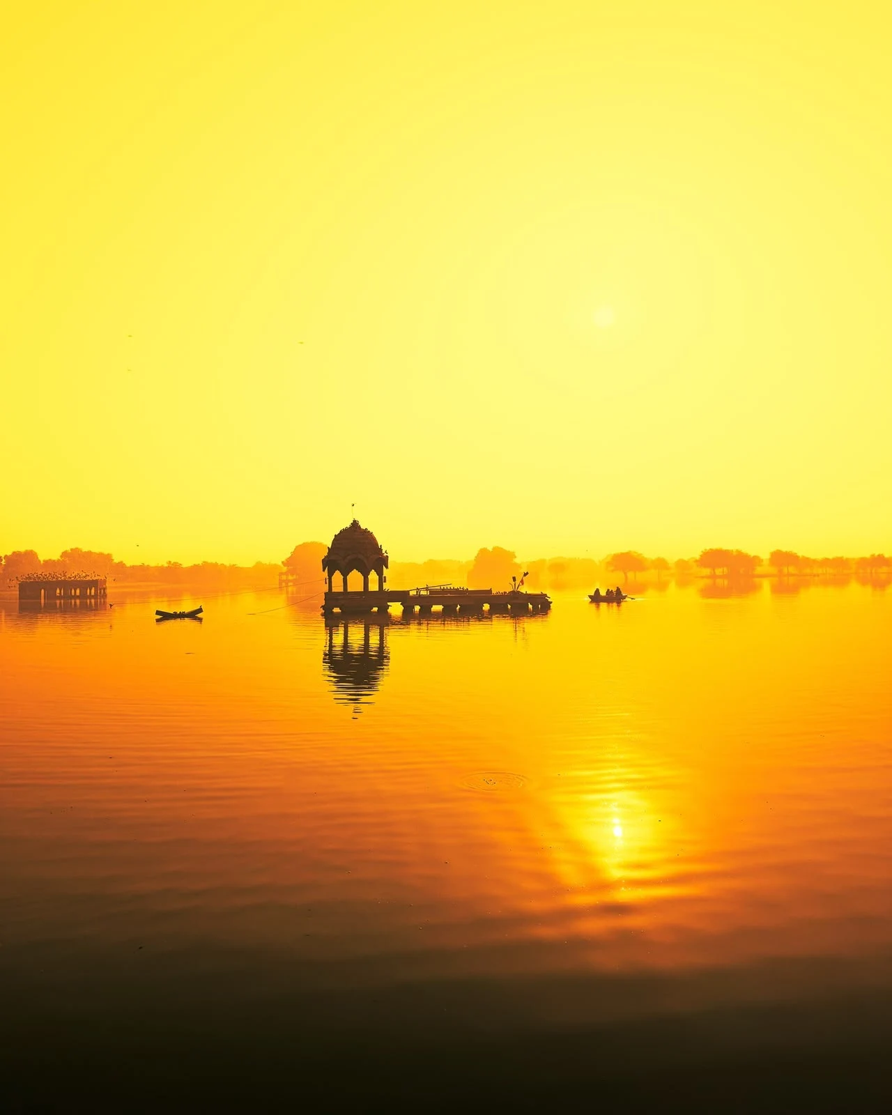 Golden light over the pavilions and reflections of Gadisar Lake